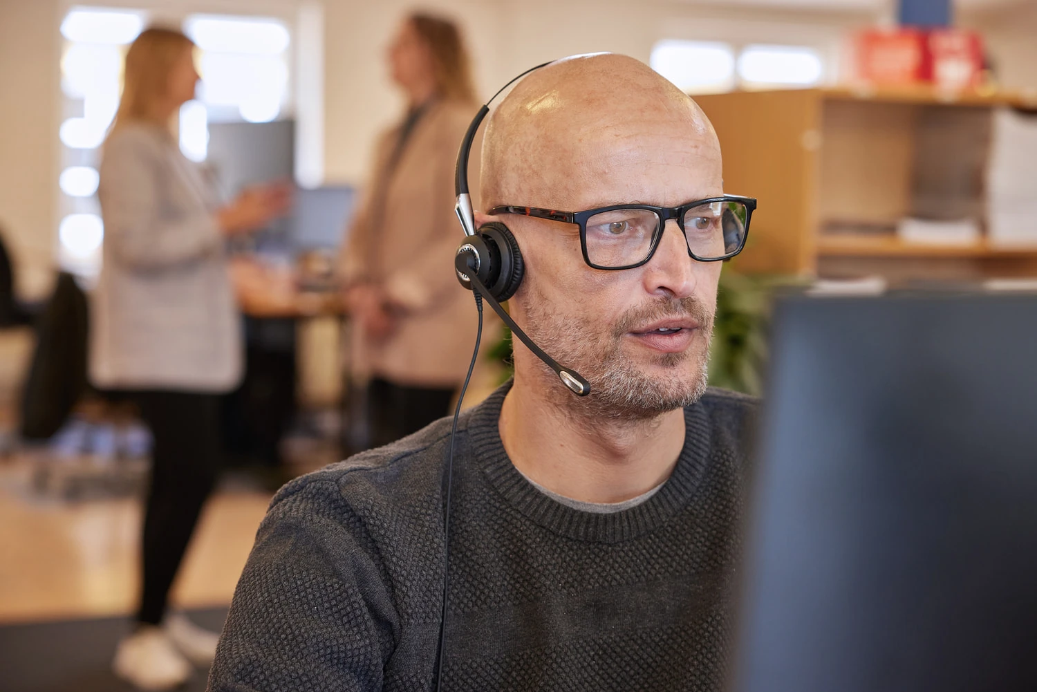 A man looking at a computer and people in the background at JS Danmark