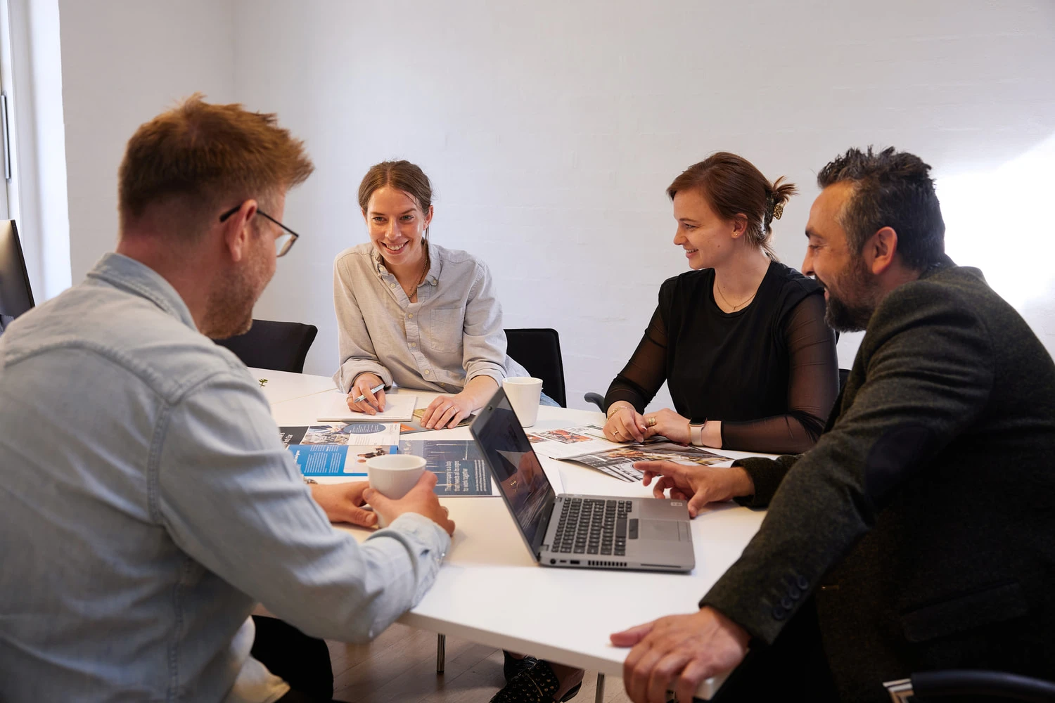 Four people in a conference room looking at brochures and smiling.